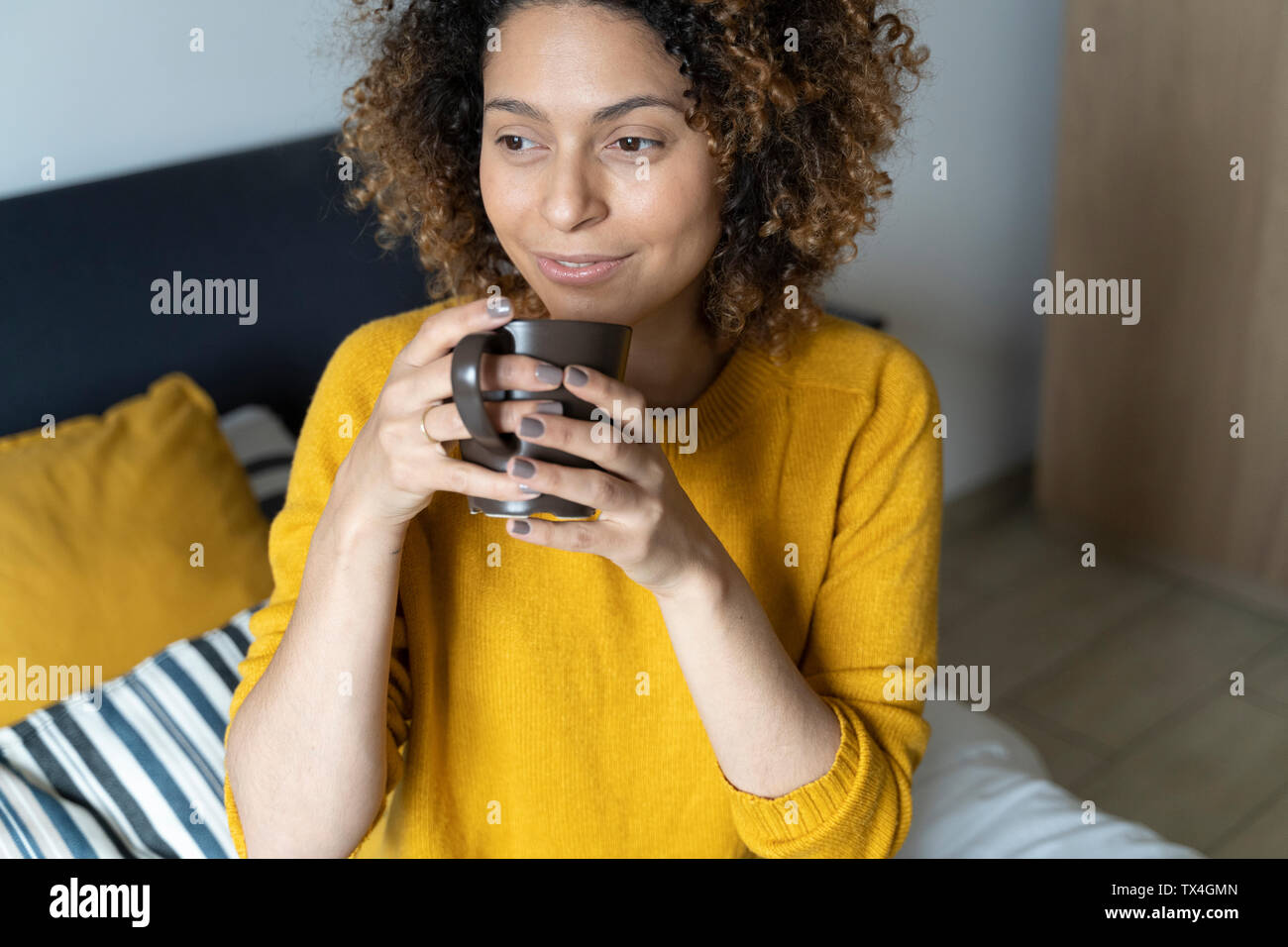 Donna seduta sul letto, prendendo una pausa, bere caffè Foto Stock