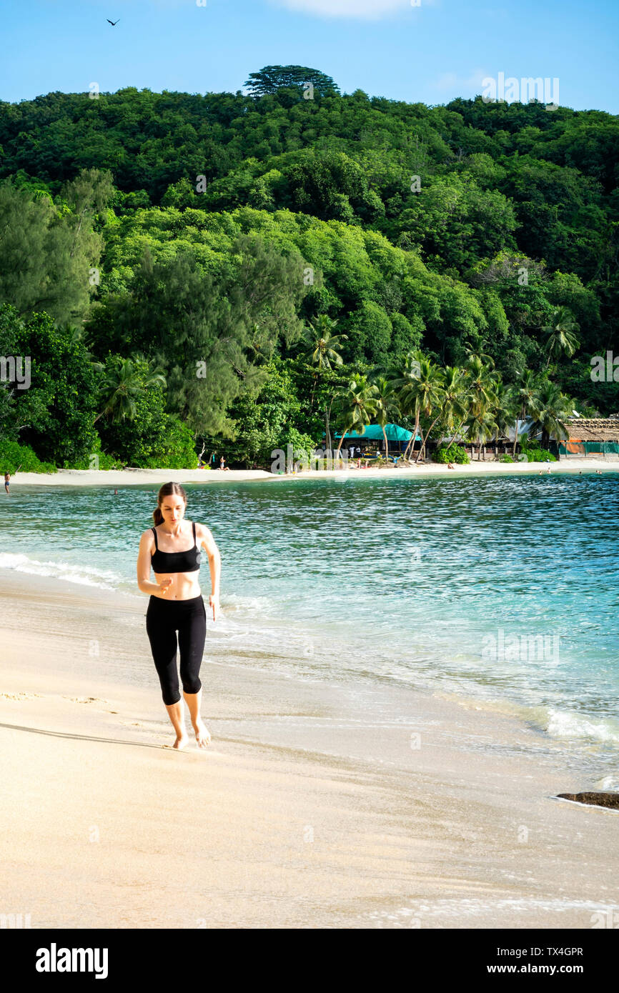 Seychelles, Mahe, Takamaka Beach, donna matura jogging sulla spiaggia Foto Stock