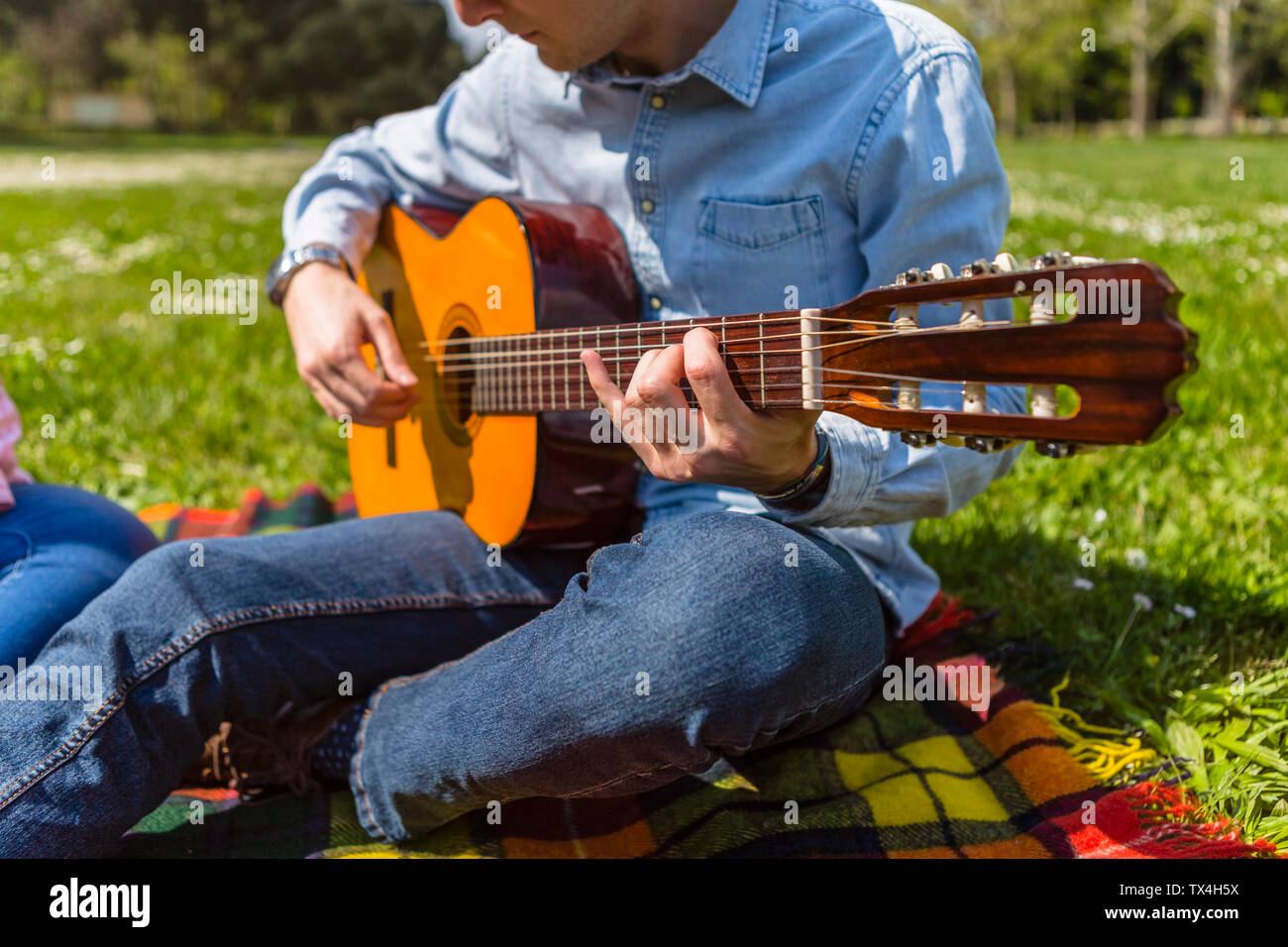 Giovane uomo a suonare la chitarra in un parco Foto Stock