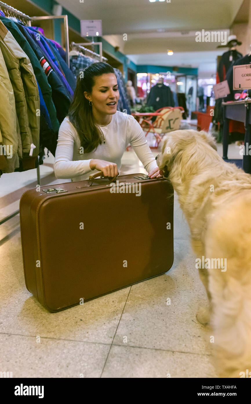 Donna con cane e vecchia valigia in una boutique vintage Foto Stock