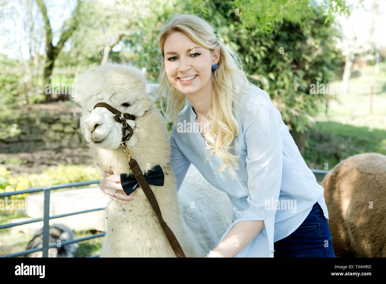 Ritratto di donna sorridente con il bianco alpaca indossando briglia e il filtro bow tie Foto Stock
