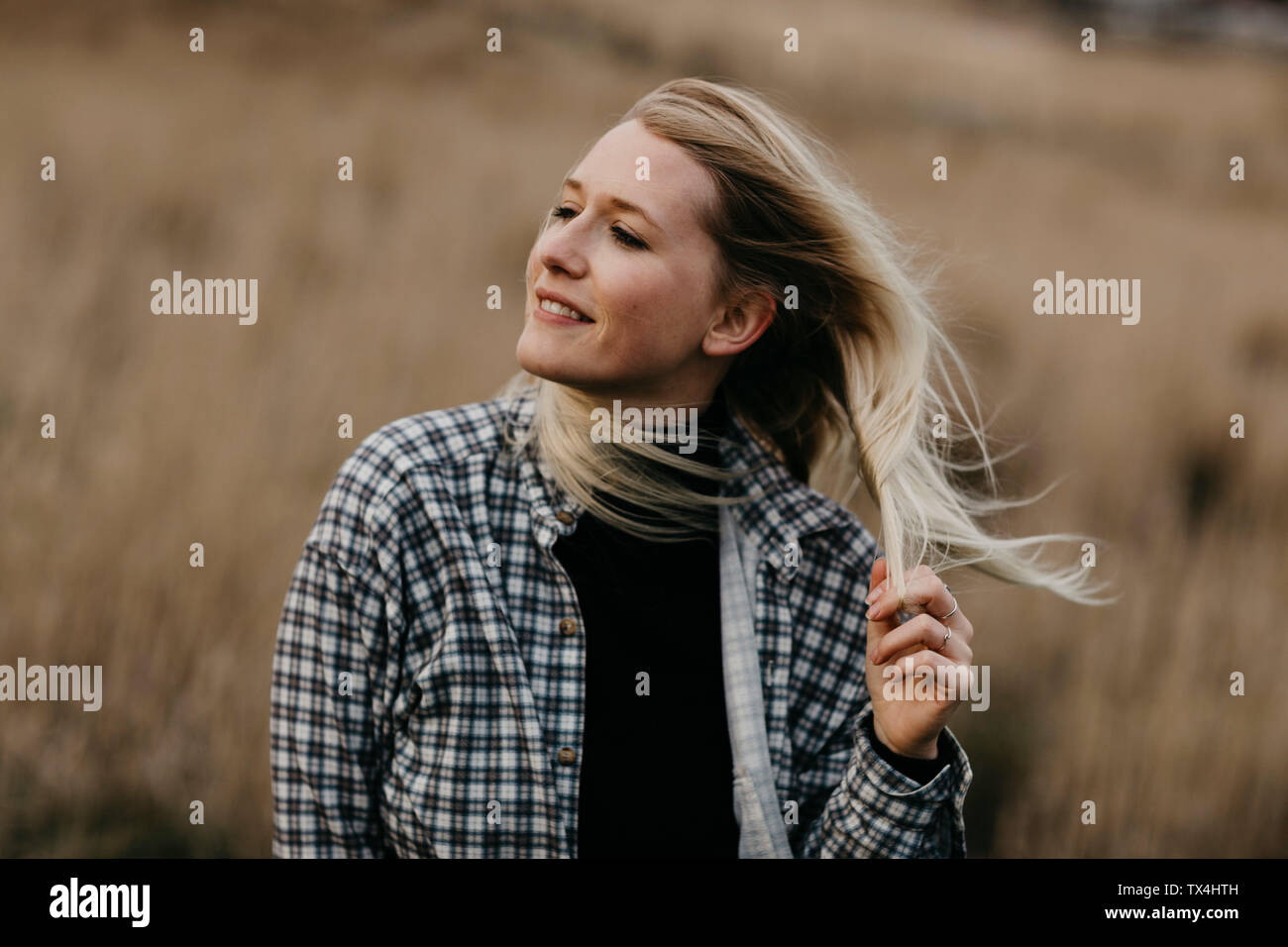 Regno Unito, Scozia, Highland, ritratto di sorridente giovane donna nel paesaggio rurale Foto Stock