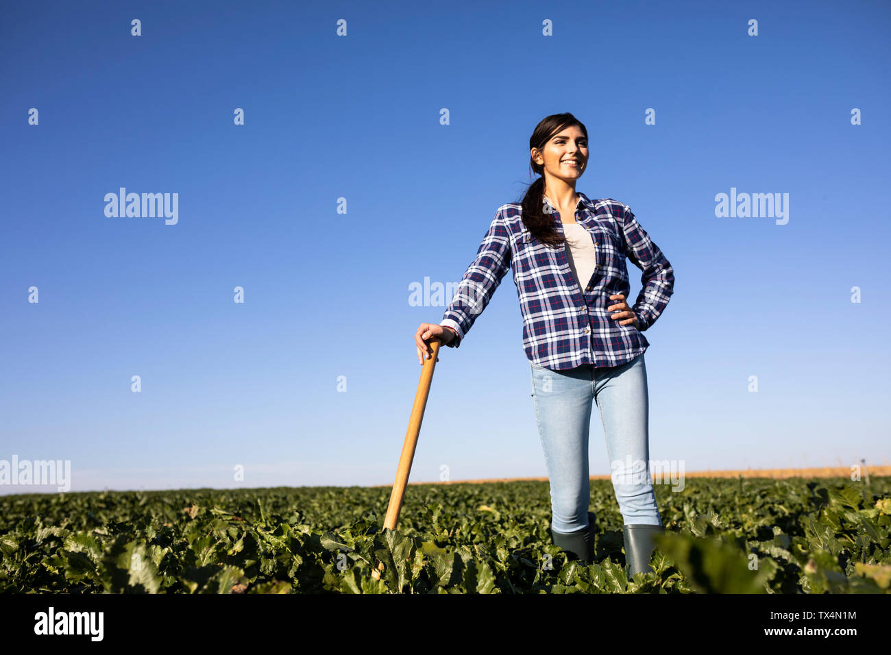 Donna giovane agricoltore con la zappa sul campo Foto Stock