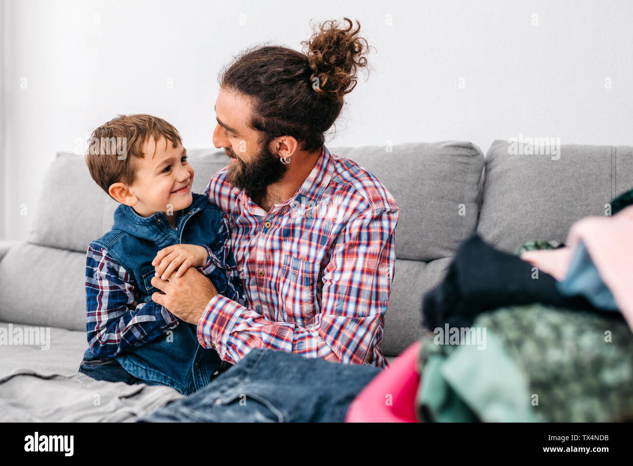 Padre e figlio seduti insieme sul lettino la piegatura servizio lavanderia Foto Stock