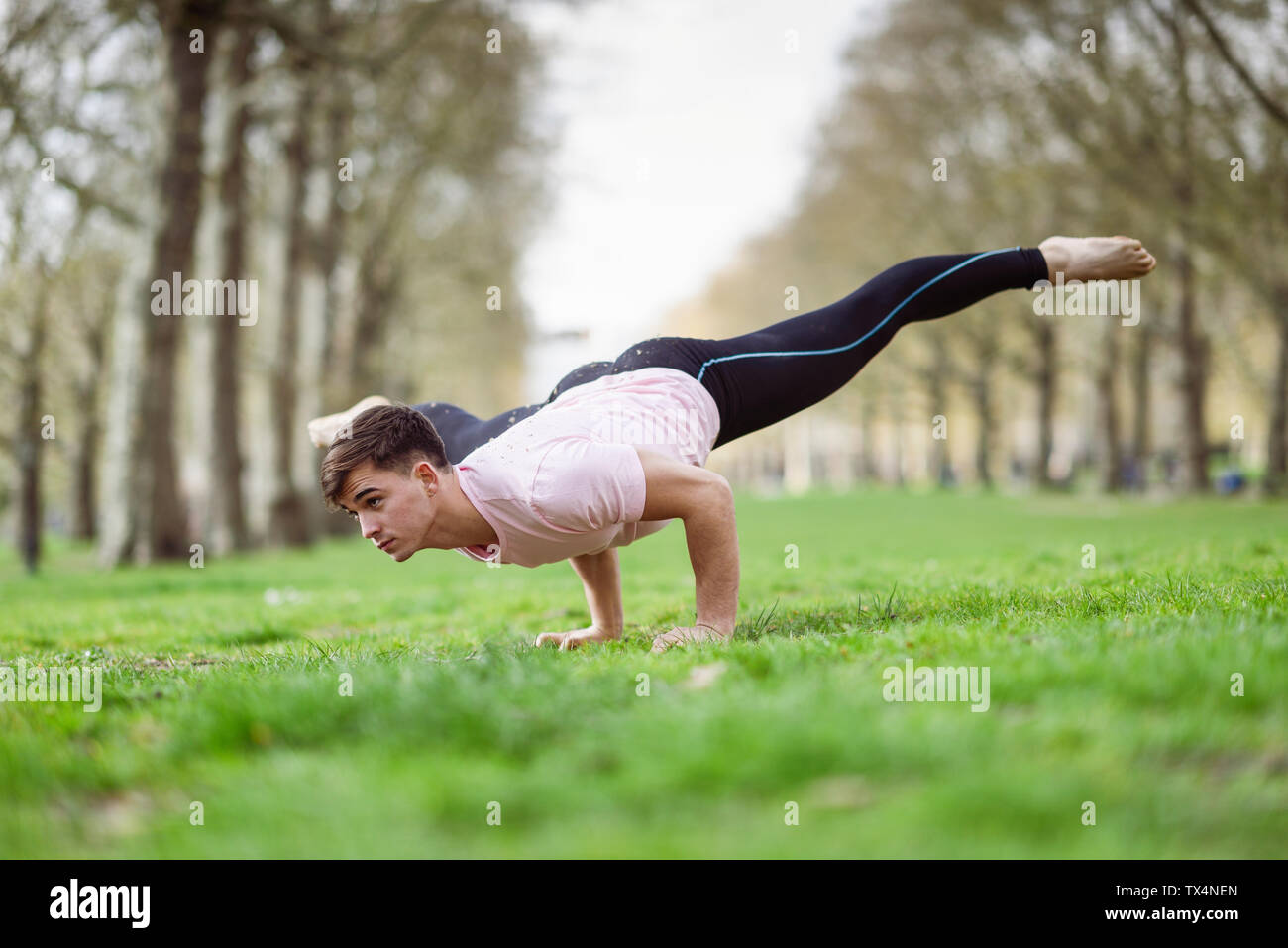 Giovane uomo facendo ginnastica acrobatica in un parco urbano Foto Stock