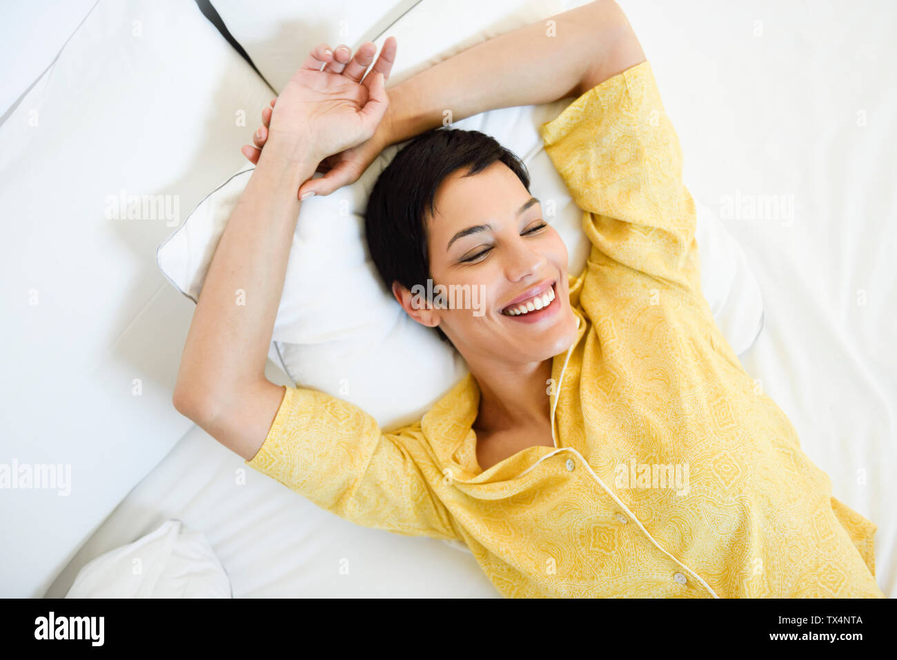 Sorridente giovane donna giaceva a letto Foto Stock
