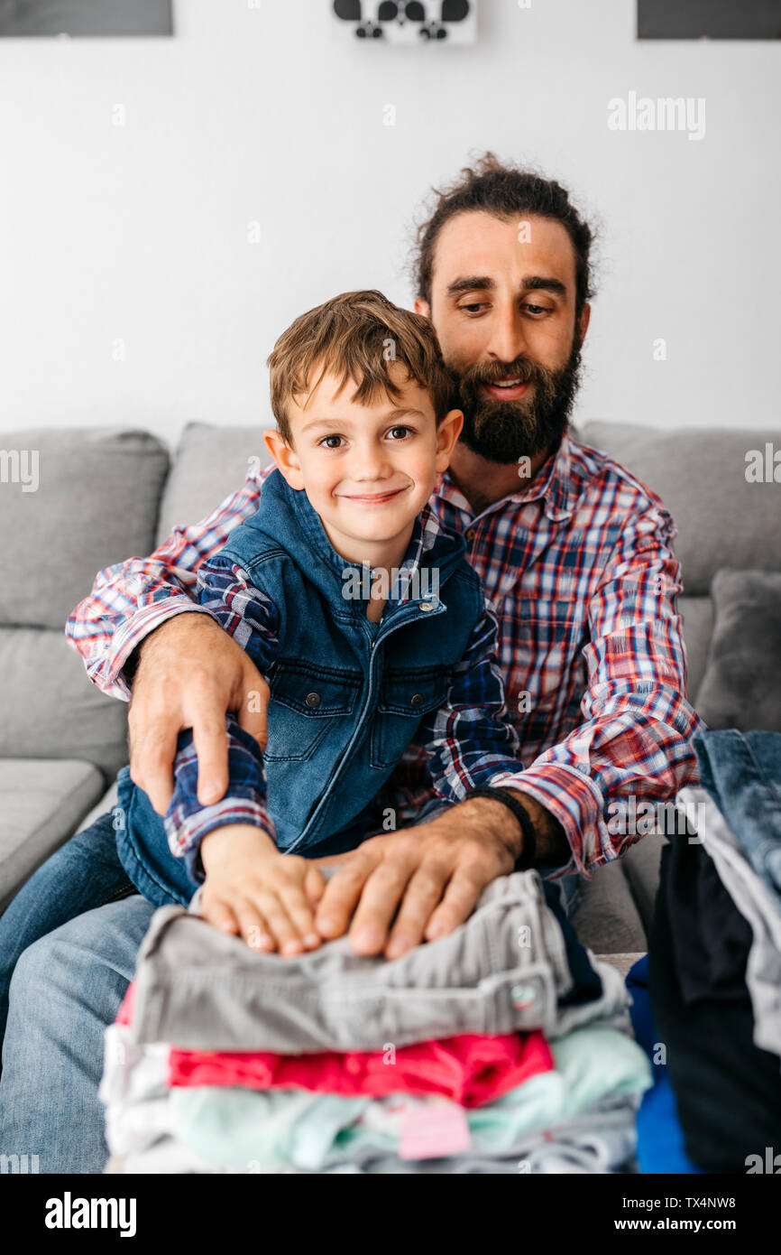 Ritratto di padre e figlio seduti insieme sul lettino la piegatura servizio lavanderia Foto Stock
