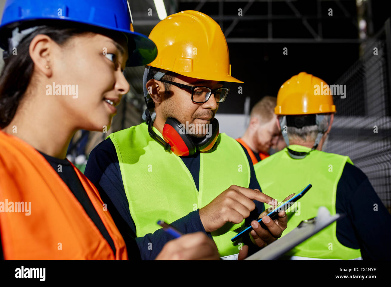 Di sesso maschile e lavoratori di sesso femminile con appunti e tablet parlando in fabbrica Foto Stock
