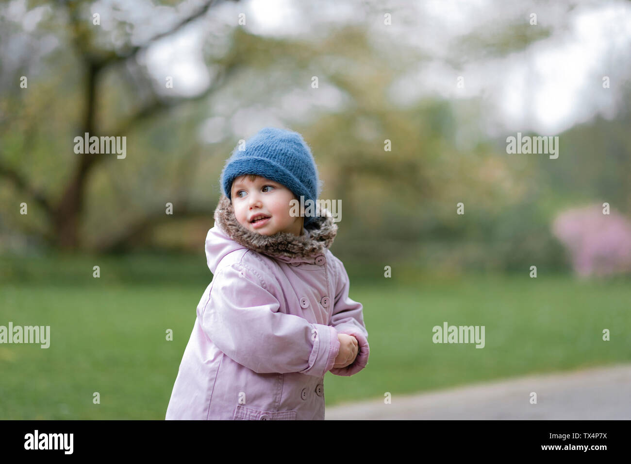 Ritratto di bambina in un parco blu che indossa un cappello e cappotto rosa Foto Stock