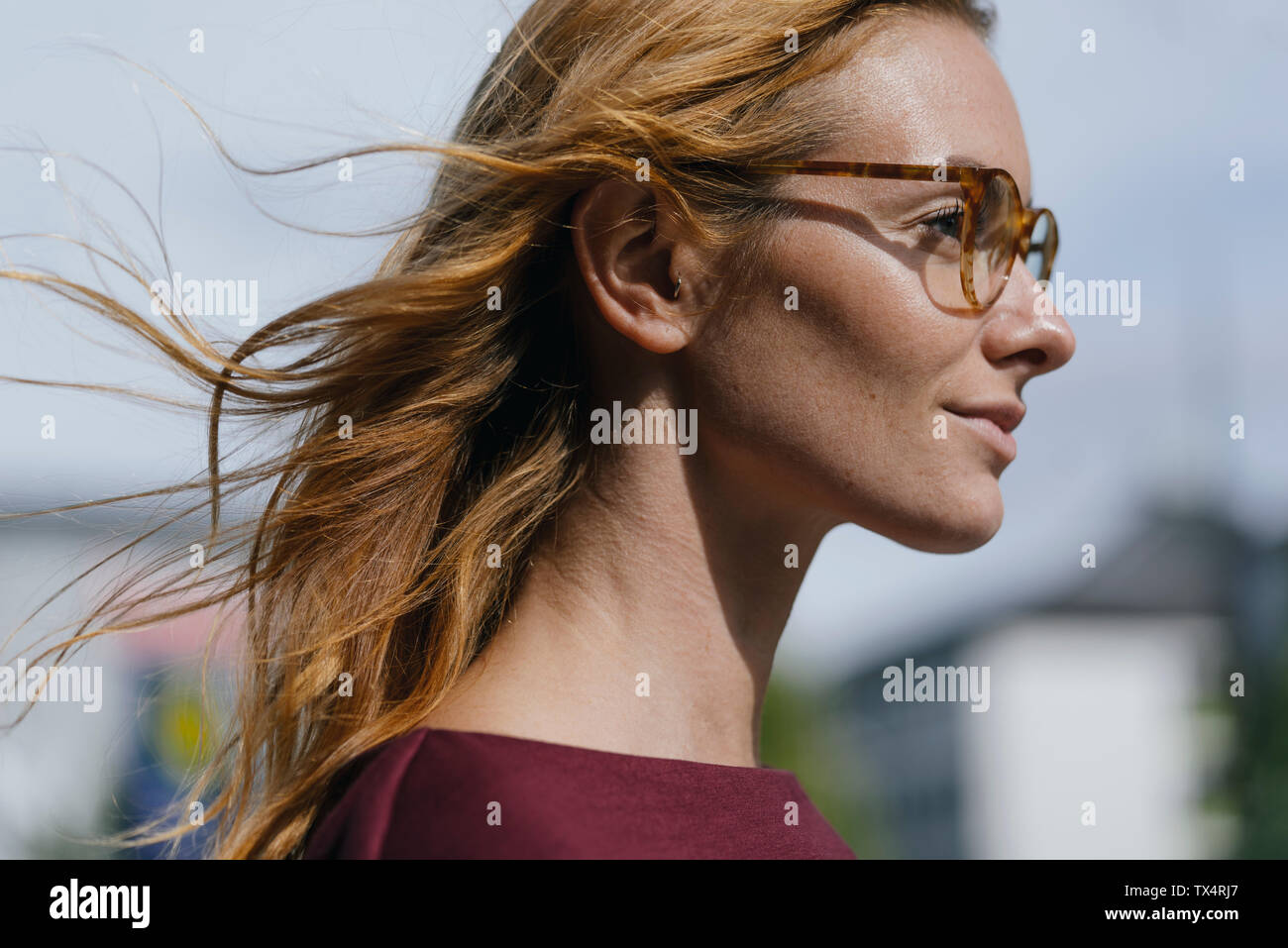 Profilo di giovane donna con occhiali e capelli spazzate dal vento Foto Stock
