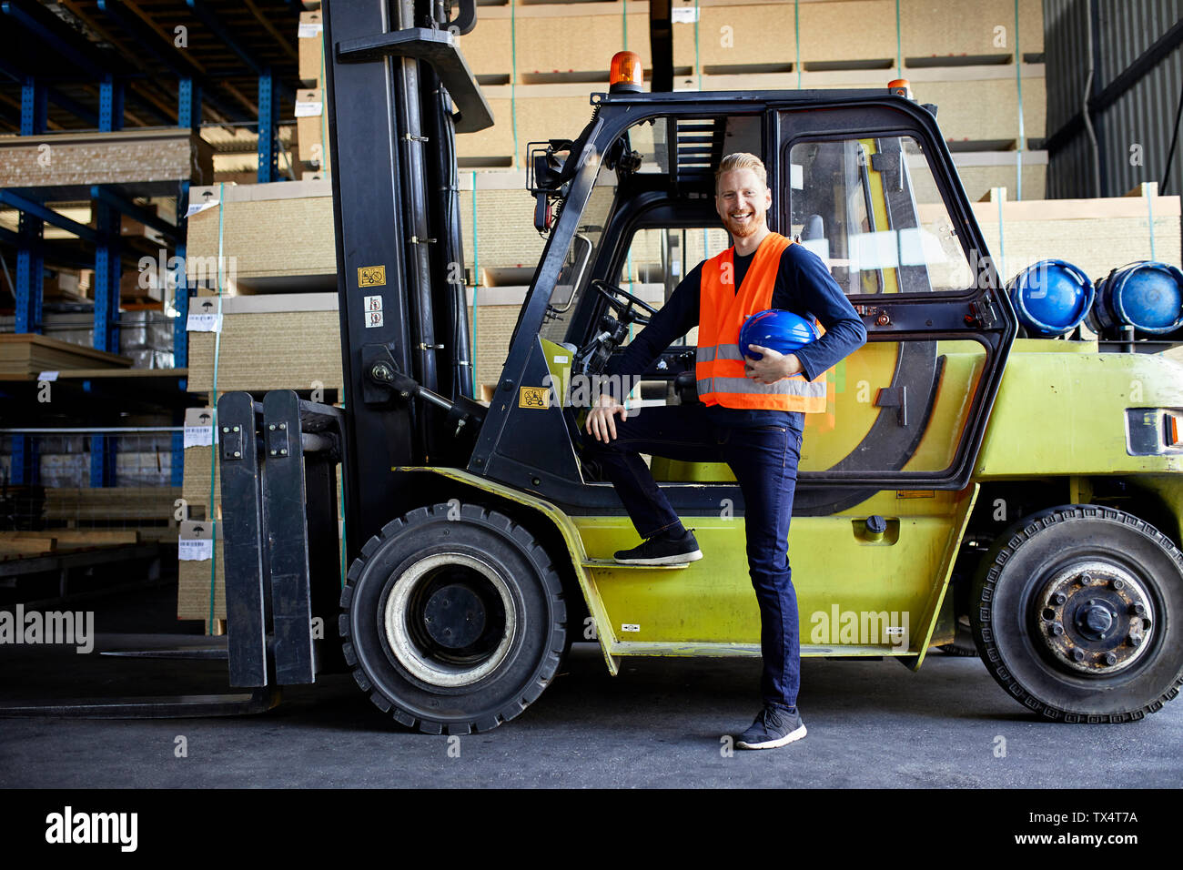 Ritratto di felice lavoratore presso il carrello elevatore in fabbrica Foto Stock