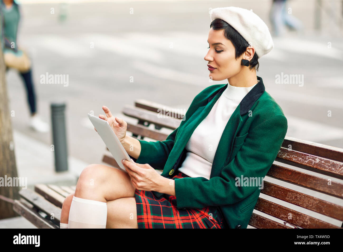 Moda giovane donna seduta su una panchina con tablet Foto Stock
