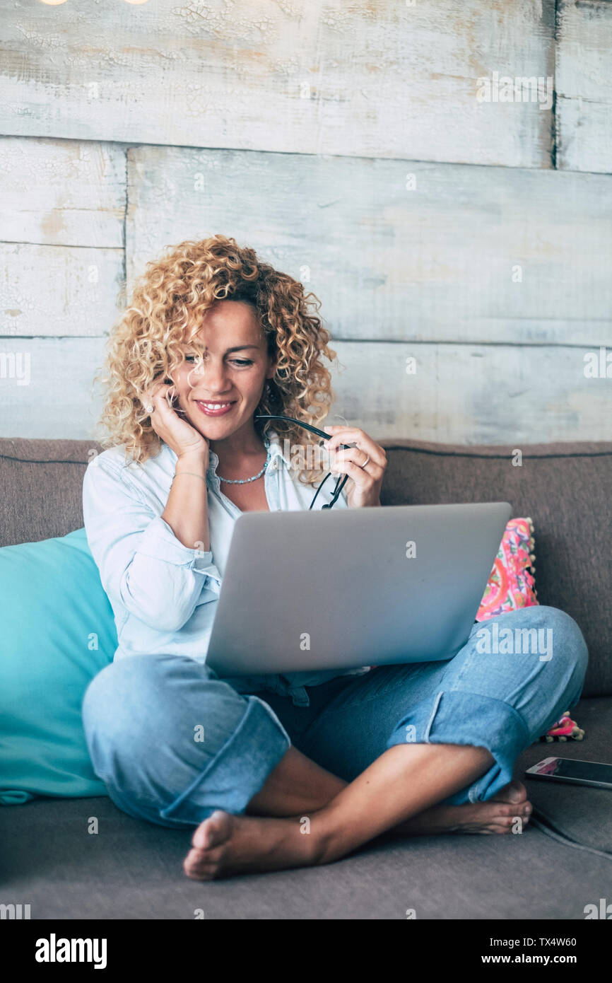 Donna che utilizza computer portatile sul lettino a casa Foto Stock