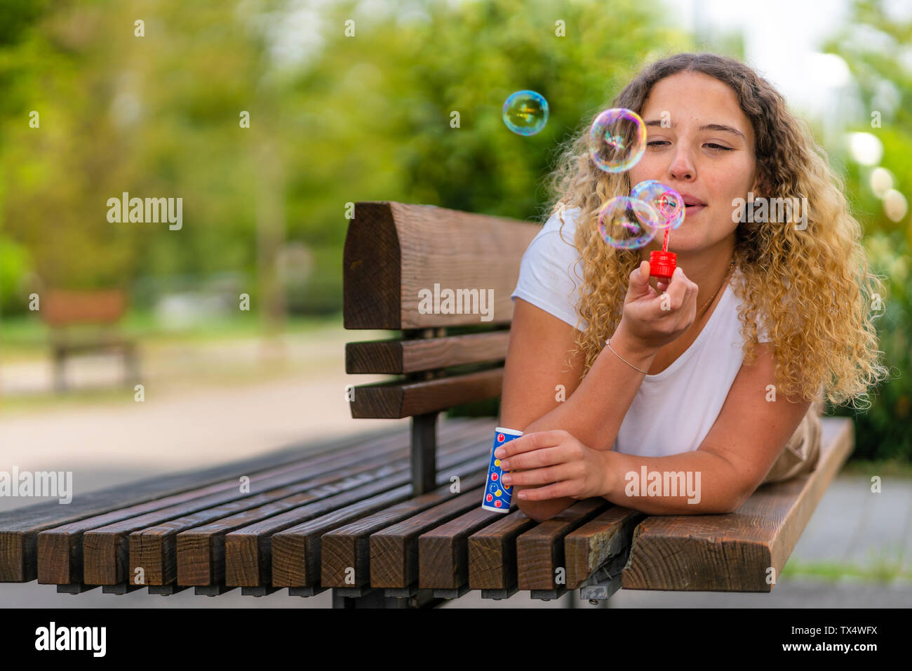 Giovane donna sdraiata su un banco di lavoro, soffiando bolle di sapone Foto Stock