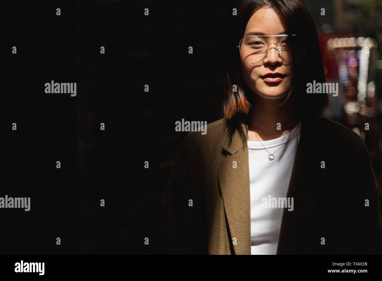 Ritratto di giovane donna che indossa gli occhiali in presenza di luce solare Foto Stock