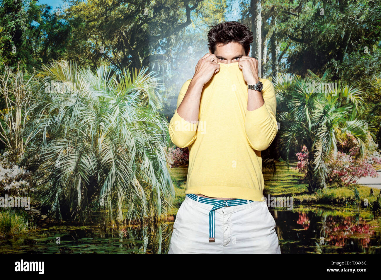 Uomo in piedi nella parte anteriore della carta da parati foto, nascondendo nel suo ponticello Foto Stock