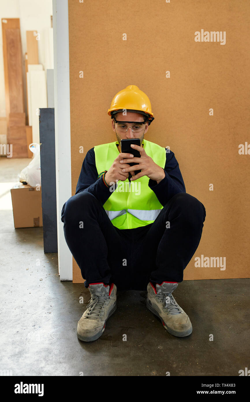 Lavoratore tramite telefono cellulare durante una pausa in fabbrica Foto Stock