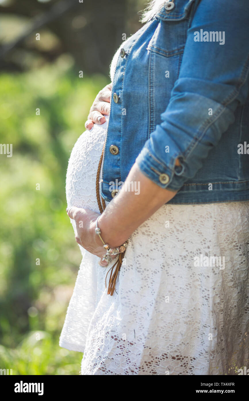 Donna incinta mentre tiene il suo ventre close up Foto Stock