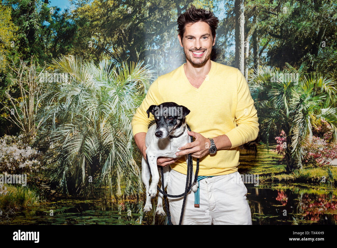 Uomo in piedi nella parte anteriore della carta da parati foto, tenendo il cane Foto Stock