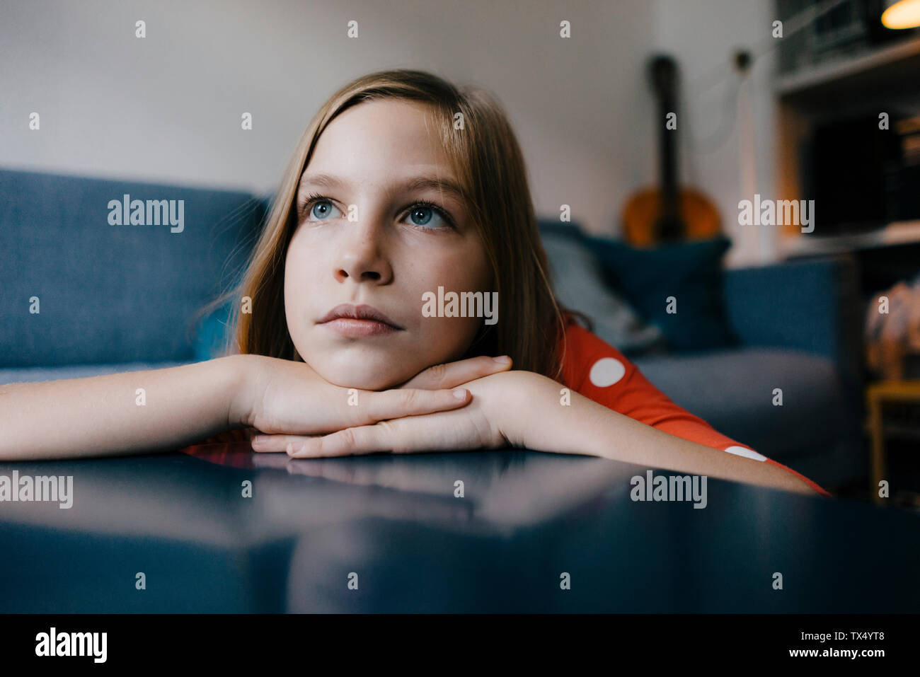 Ragazza seria in appoggio la sua testa sul tavolino da caffè a casa Foto Stock