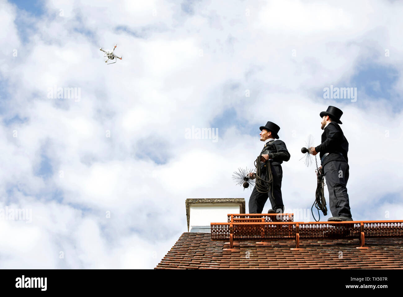 Due spazzacamini sul tetto di casa guardando il fuco Foto Stock