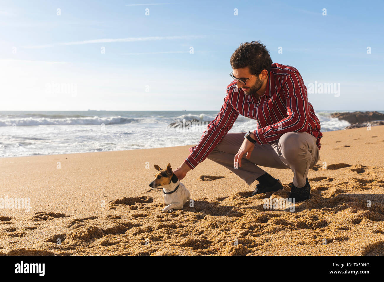 Il Portogallo, Porto, giovane di accarezzare il suo cane sulla spiaggia Foto Stock