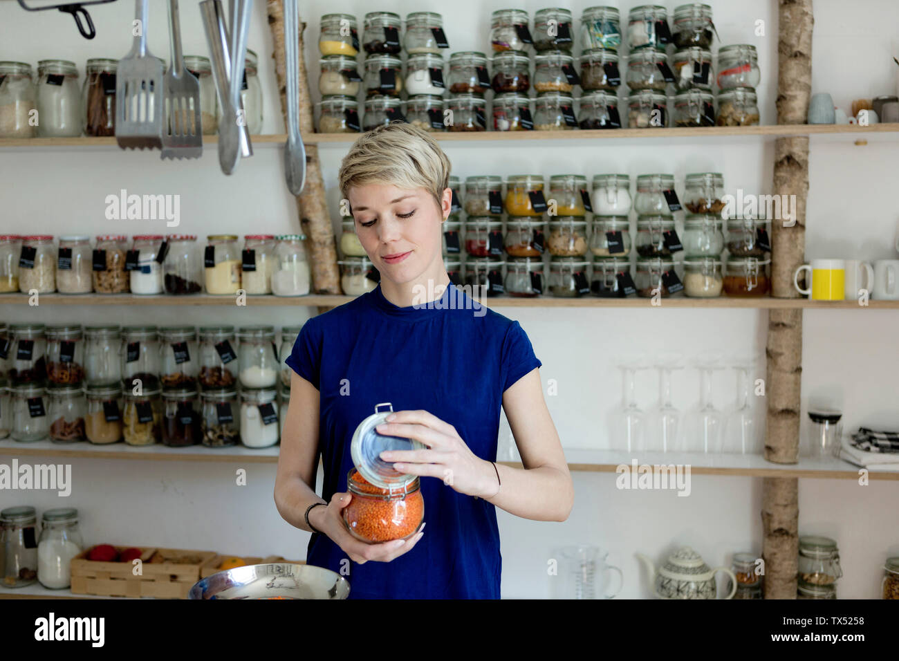 Donna vaso di apertura nella parte anteriore del ripiano di spezie in cucina Foto Stock