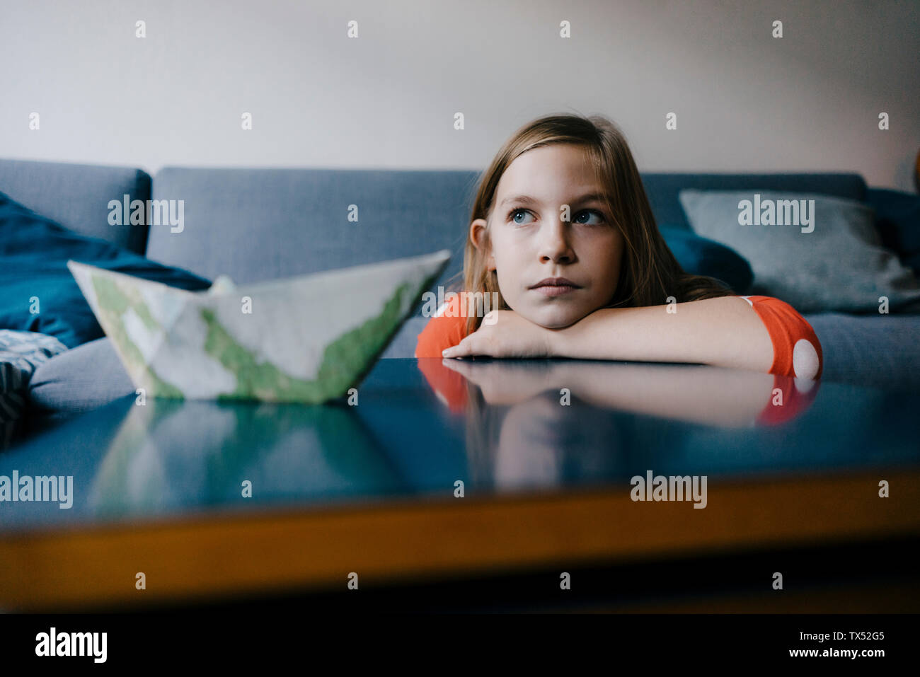Ragazza seria in appoggio la sua testa sul tavolino da caffè a casa Foto Stock