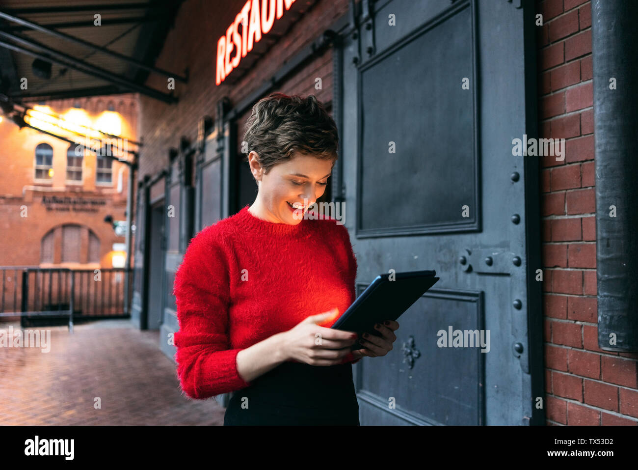 Germania Berlino, sorridendo il manager del ristorante utilizzando tavoletta digitale all'aperto Foto Stock