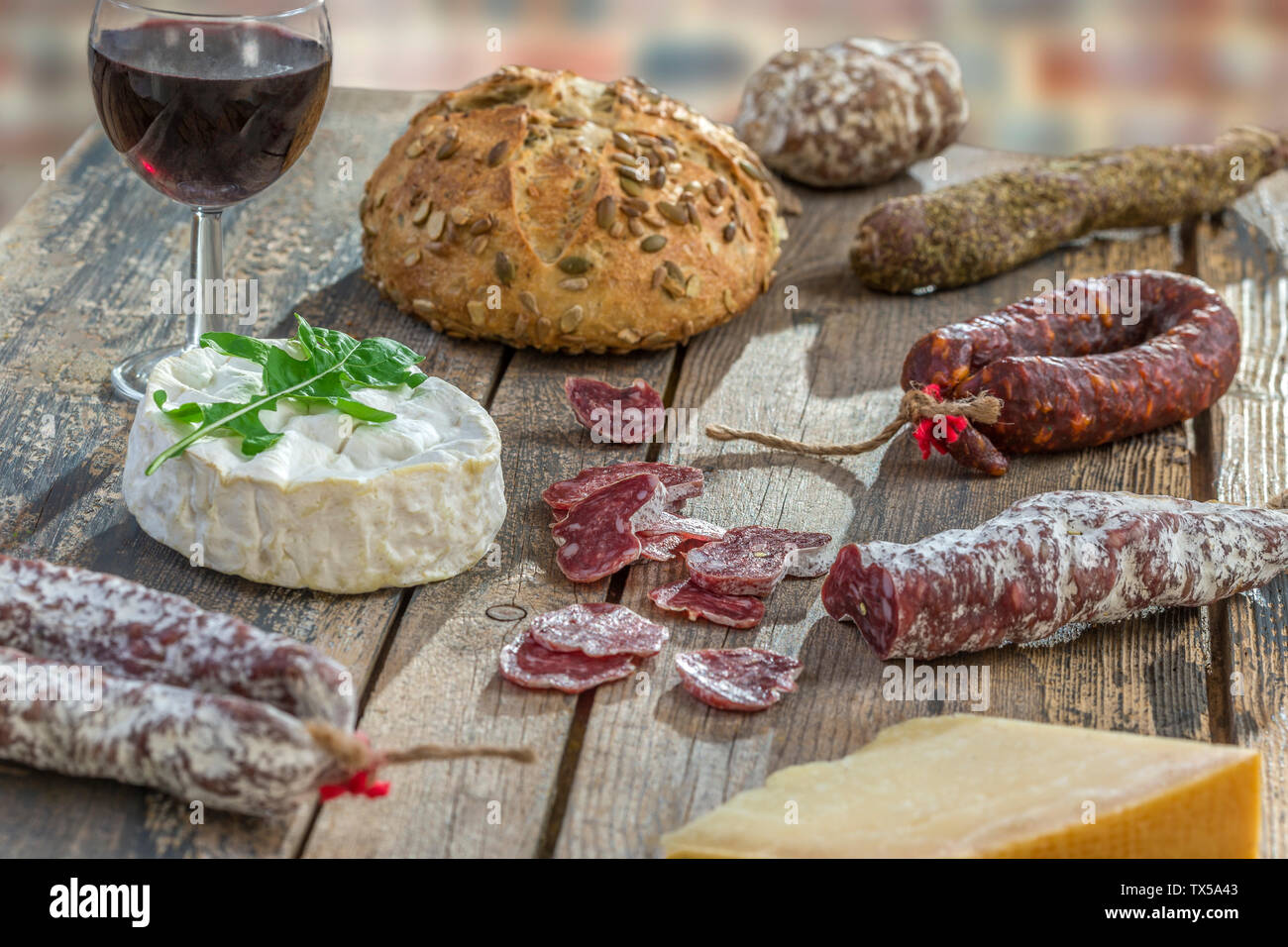 Spuntini francese con il vino - vari tipi di formaggi, pane secco , affettati di salumi misti, salumi, vite rossa su uno sfondo grigio. Vista dall'alto. Foto Stock