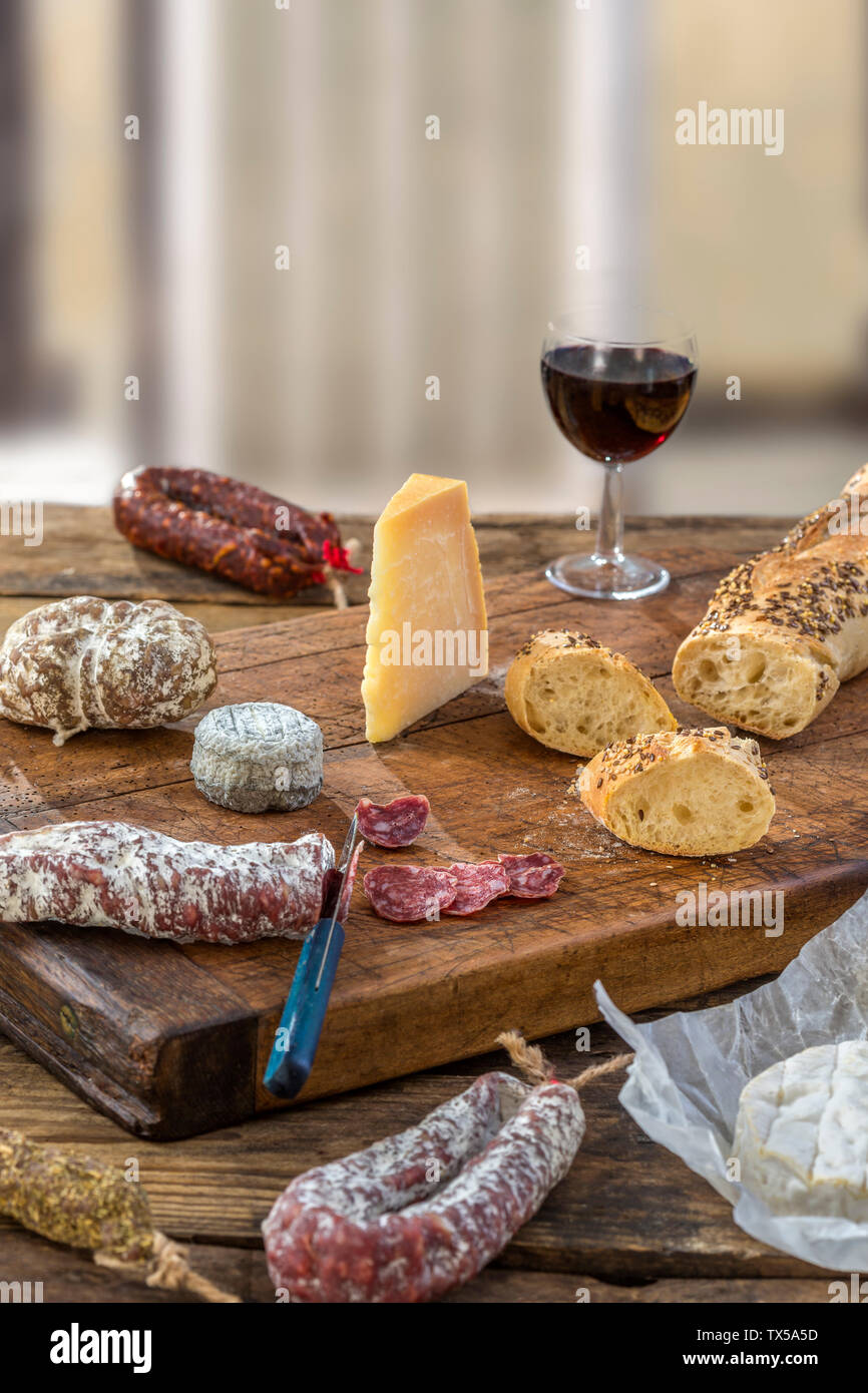Spuntini francese con il vino - vari tipi di formaggi, pane secco , affettati di salumi misti, salumi, vite rossa su uno sfondo grigio. Foto Stock
