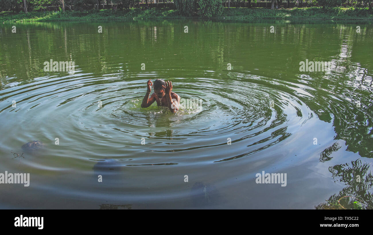 Estate ramna parco 23 giu,2019 Dhaka bangladesh.a uomo sta facendo un bagno nello stagno del parco ramana a causa di esaurimento del calore.Nazmul Islam / alamy stock vivere Foto Stock
