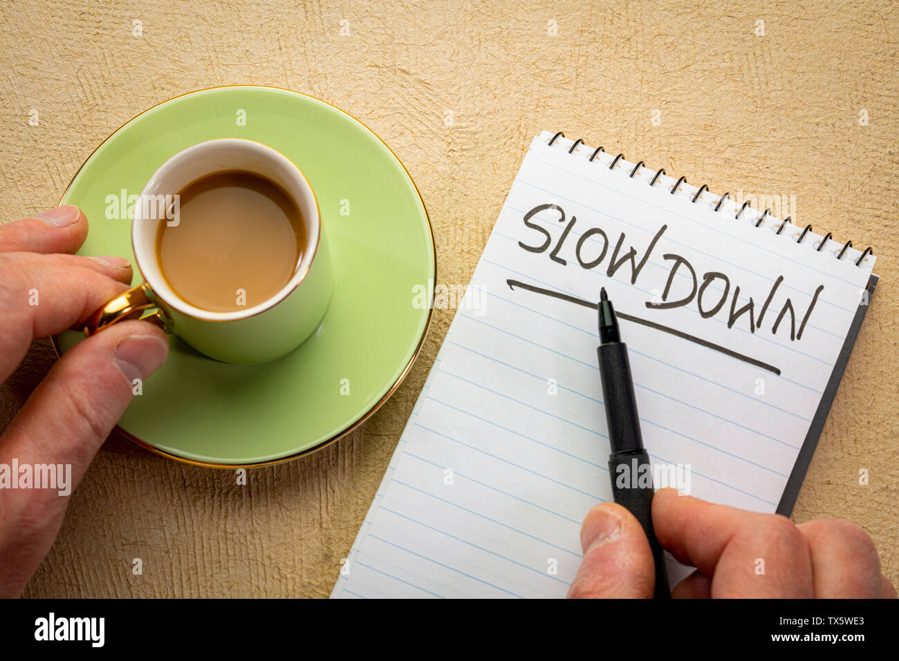 Rallentare di consulenza o di promemoria - la grafia in un notebook a spirale con una tazza di caffè Foto Stock