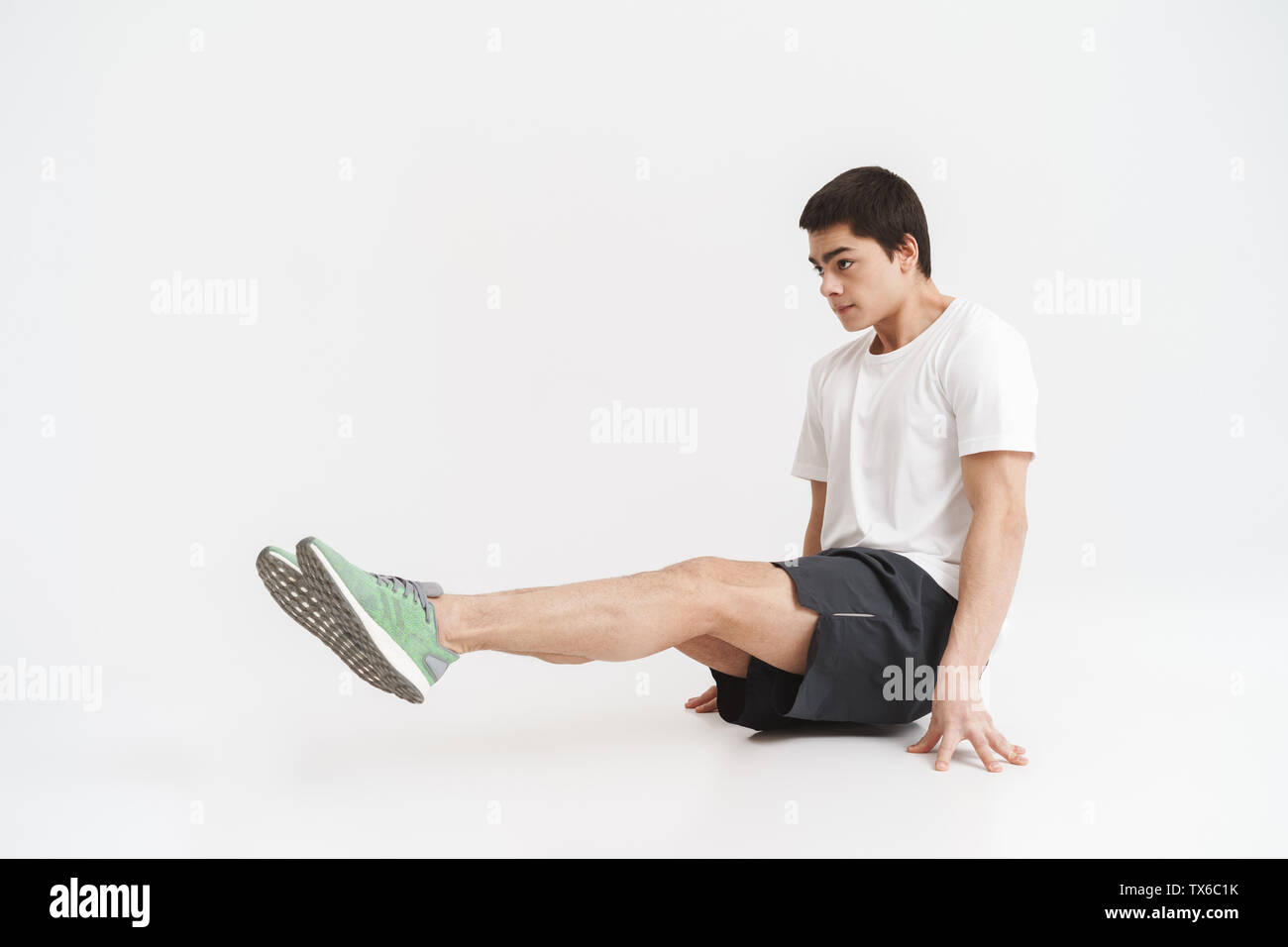 Lunghezza completa di un sano montare sportivo facendo esercizi di nucleo isolato su sfondo bianco Foto Stock