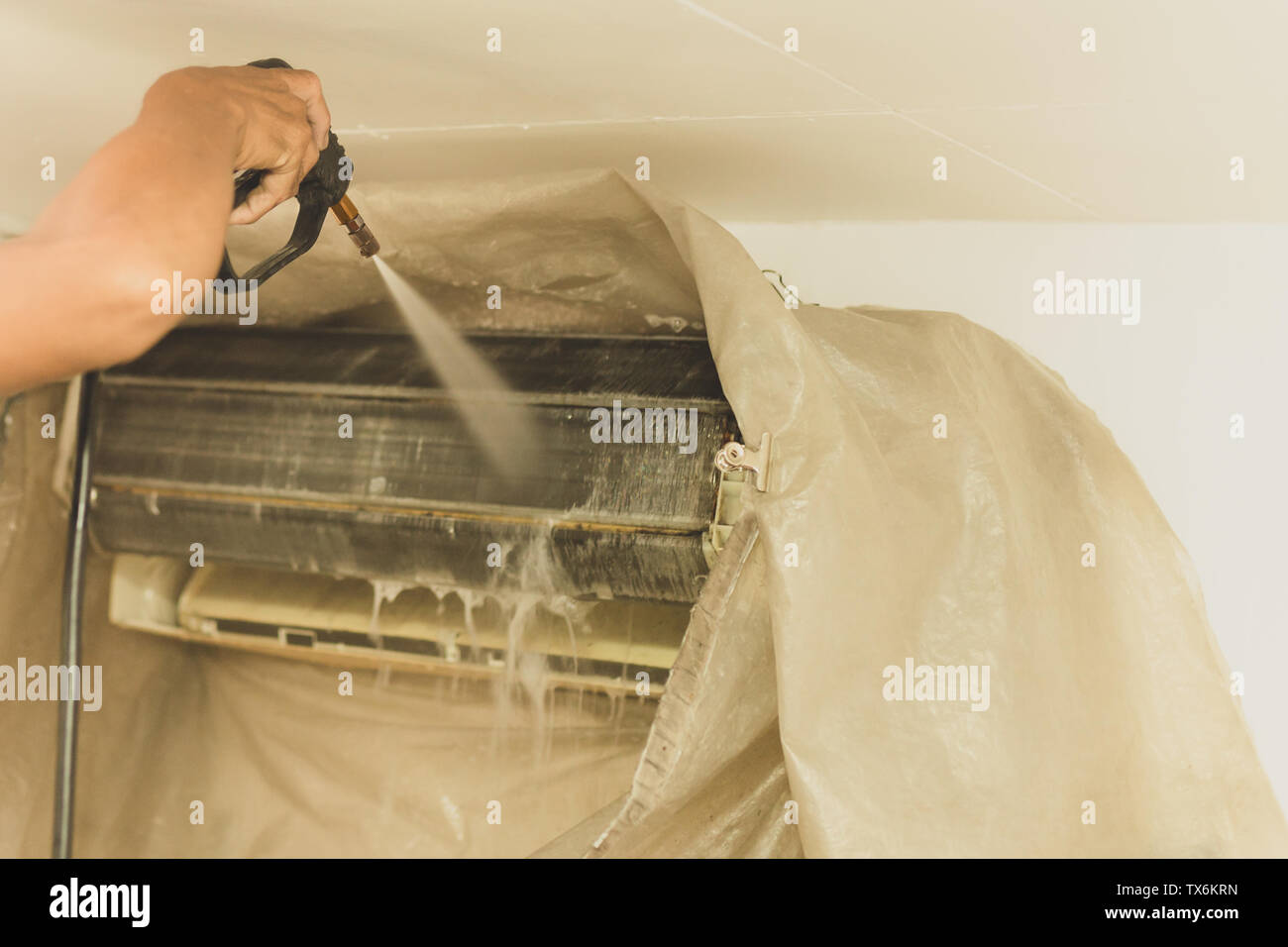 Lavoratore parete pulizia condizionatore d'aria con acqua ad alta pressione della pompa a getto a casa. Foto Stock