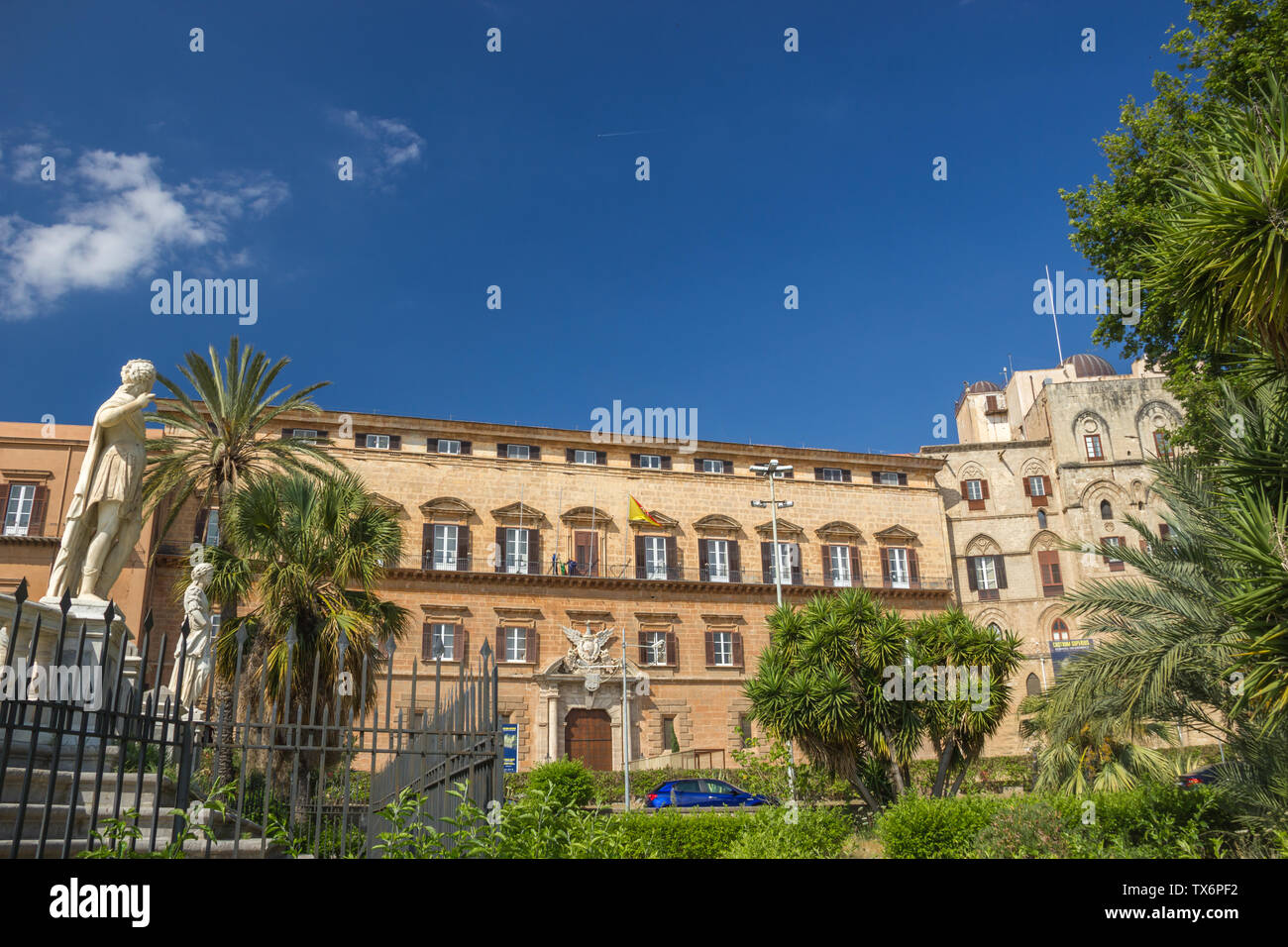 Palermo Sicilia, facciata del patrimonio storico del Palazzo dei Normanni e il suo giardino, palazzo reale con la statua e le palme Foto Stock