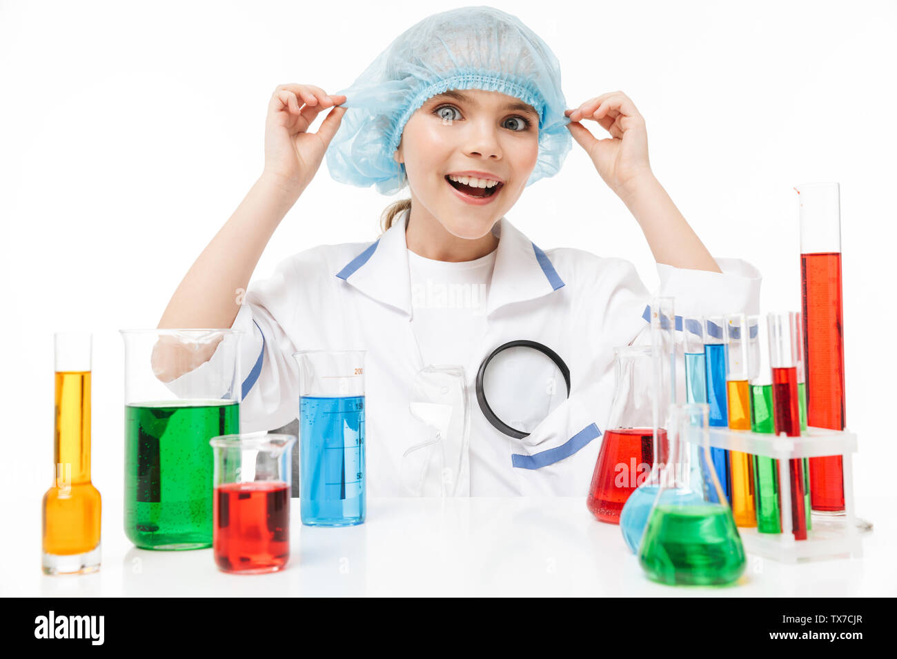 Ritratto di divertente bambina in bianco camice da laboratorio facendo esperimenti di chimica con liquido multicolore in tubi di test isolato su bianco backgrou Foto Stock