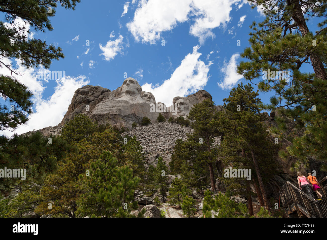 Due giovani ragazze a piedi su una scalinata sotto la roccia emposing dispone di quattro presidenti degli Stati Uniti scolpiti nel granito a Mount Rushmore National Me Foto Stock