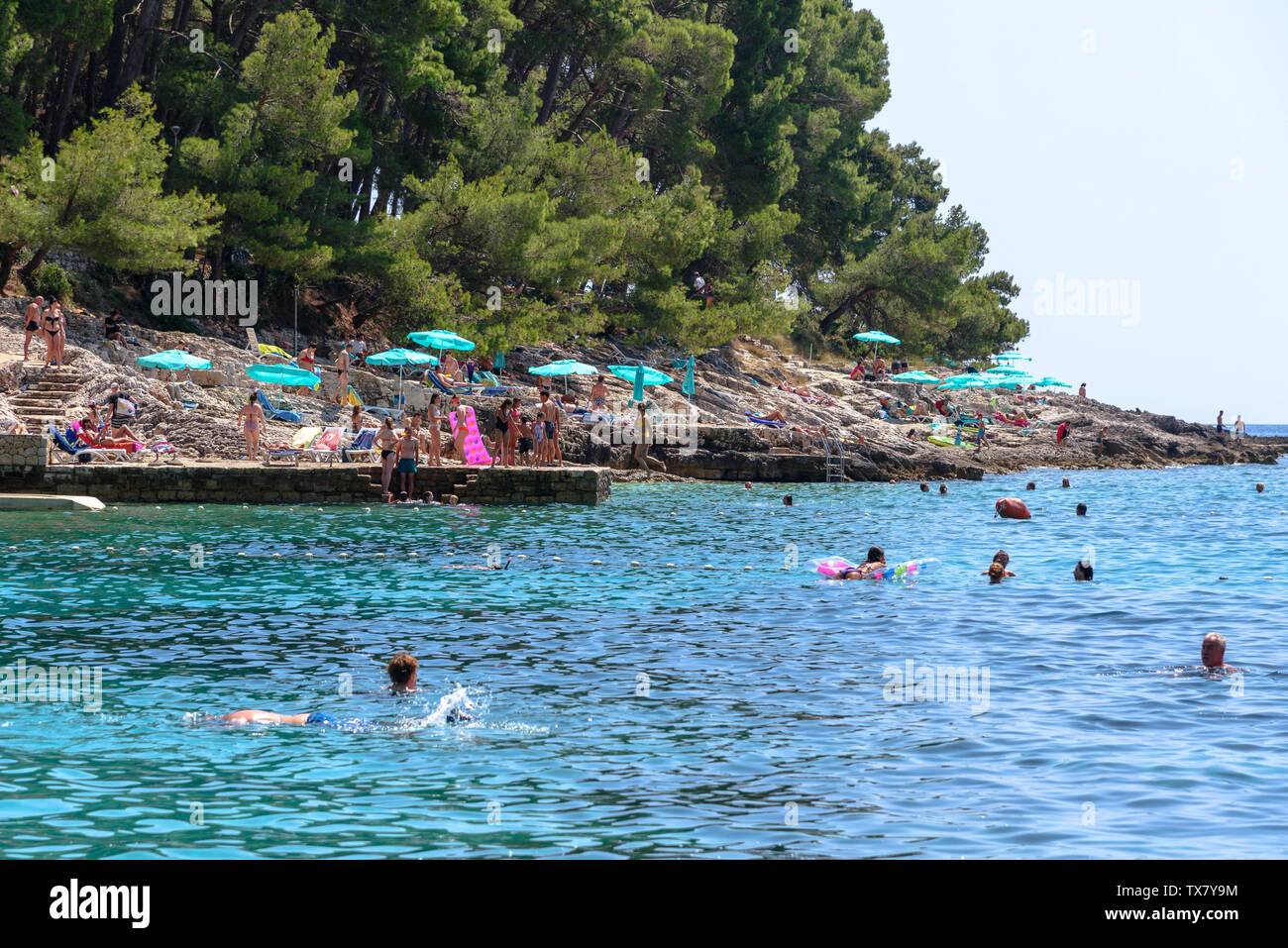 Le persone a nuotare in acqua e la concia sulle rocce di Veli žal beach in Mali Losinj, Croazia Foto Stock