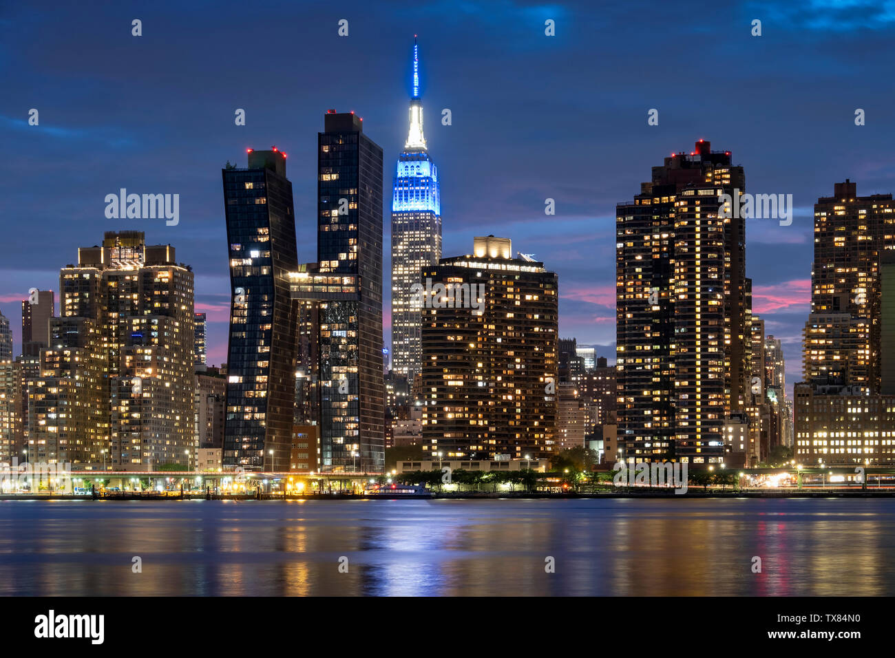 Manhatttan skyline notturno con l' Empire State Building attraverso l'East River, New York, Stati Uniti d'America Foto Stock