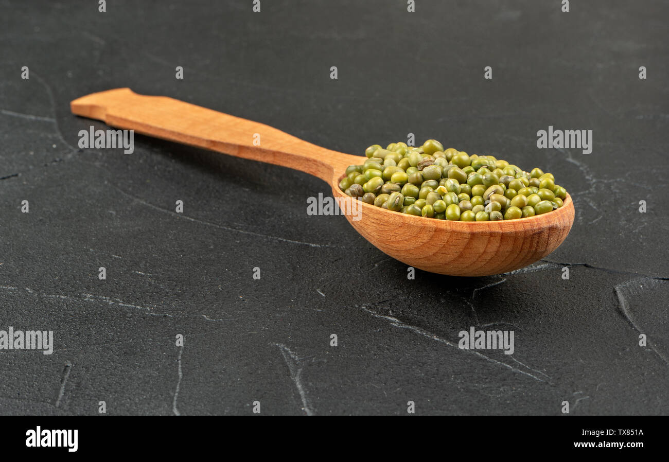 Grande cucchiaio di legno verde con nucleasi di grani sul sottofondo di calcestruzzo Foto Stock
