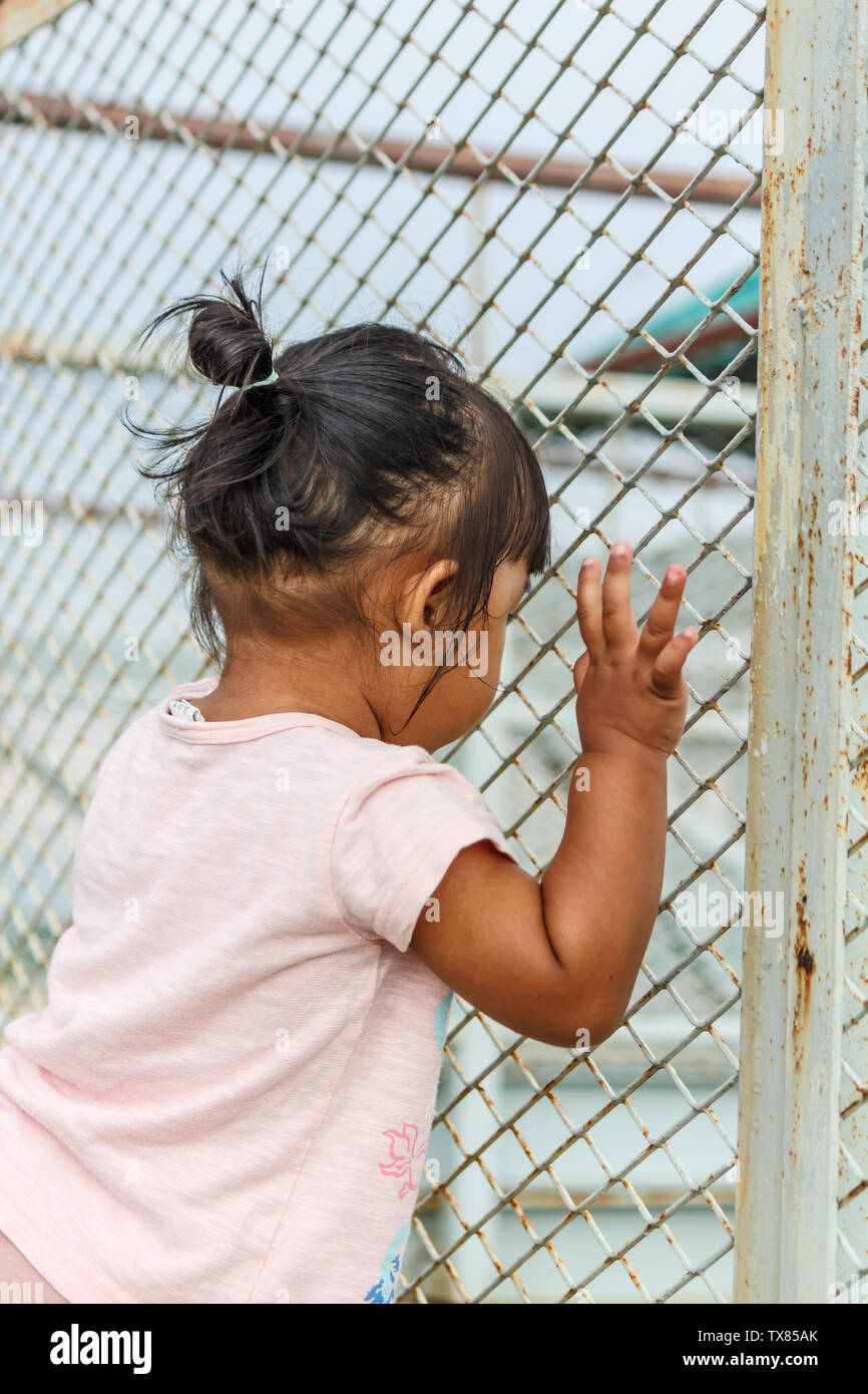 Bambino ragazza con recinzione in acciaio. .Concetto per gli abusi sui minori e la tratta di esseri umani, la criminalità e la violenza domestica,protezione di capretto Foto Stock