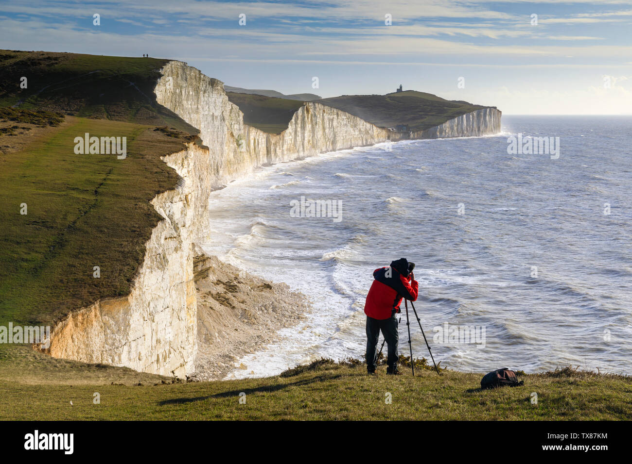 Un fotografo su una scogliera a sette sorelle con Beachy Head nella distanza. Foto Stock