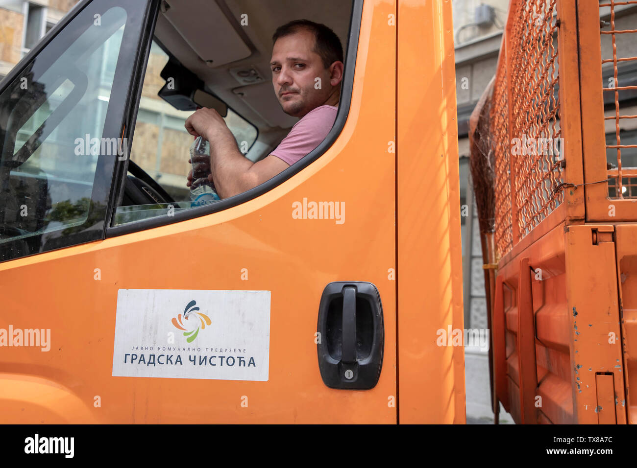 Belgrado, Serbia, 6 Giugno 2019: scene di strada con un garbage collector camionista apertura di una bottiglia di acqua Foto Stock