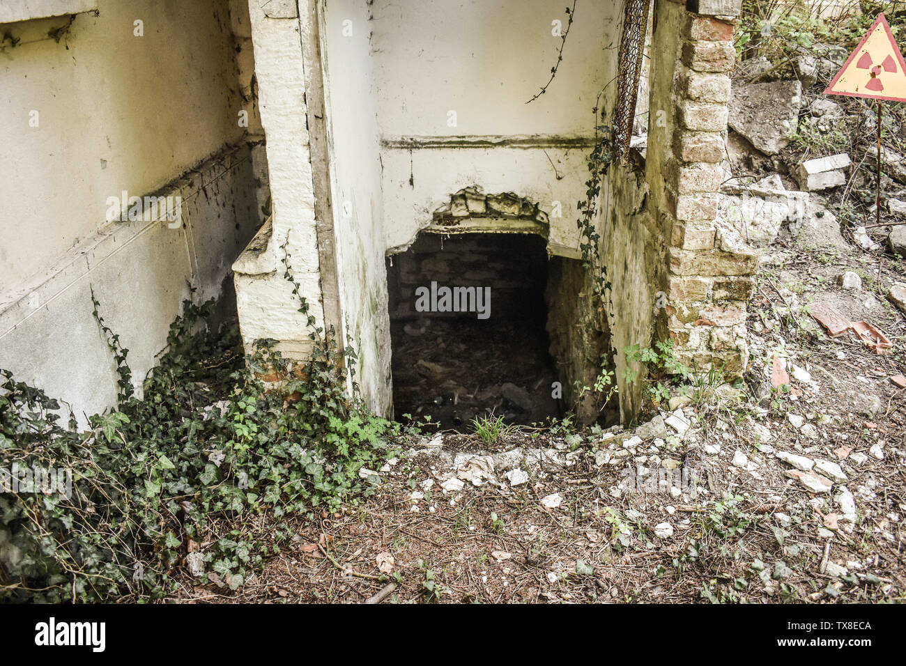 Appena scoprire nascosto camere sotterraneo dietro il muro rotto del abbandonato il vecchio edificio con segno radioaactive nella zona. Chernobyl Pripjat atmo Foto Stock
