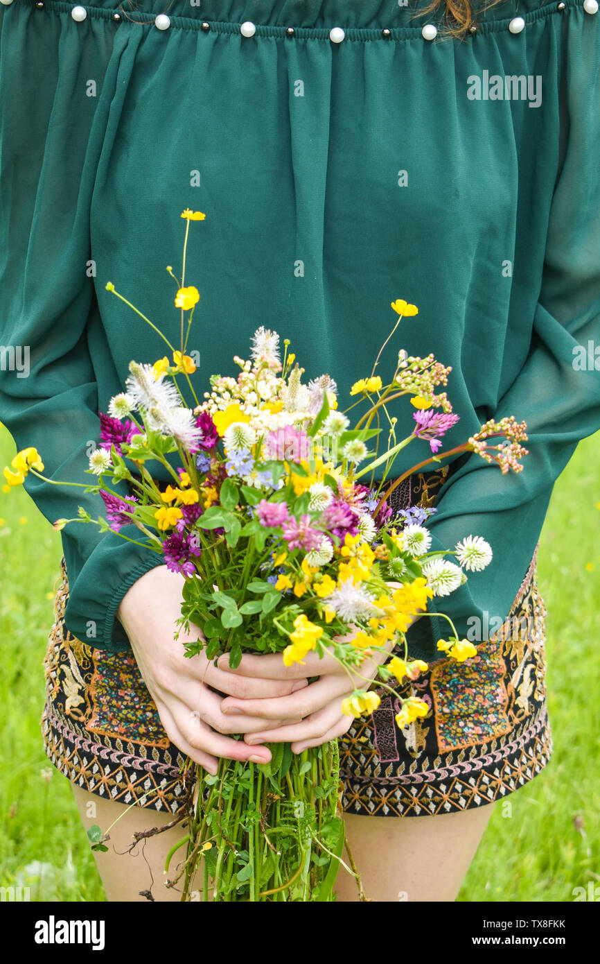 Ragazza con in mano un bel bouquet con multi-colore di fiori selvatici. Incredibile mazzo di fiori wilf nella natura. Foto Stock