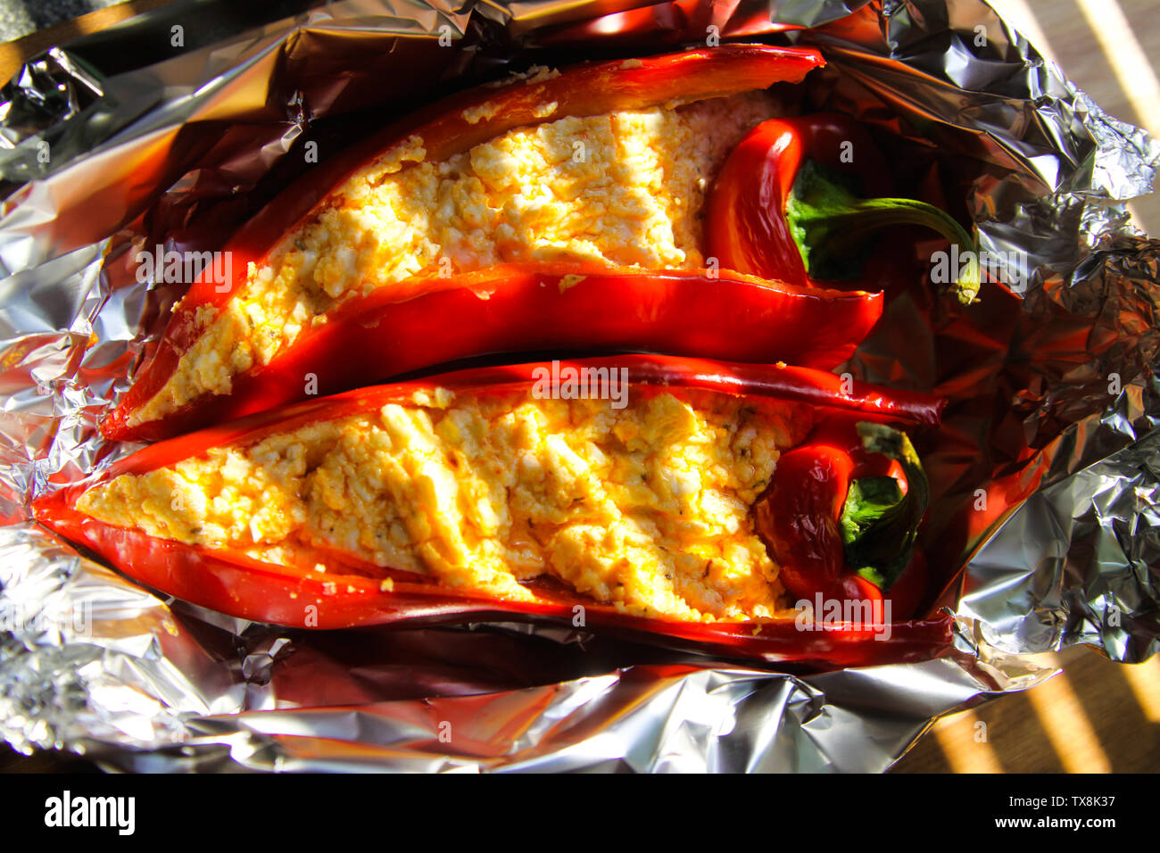 Close up farcite peperone rosso peperoni con pecora formaggio feta condito con peperoncino piccante alla griglia in un foglio di alluminio Foto Stock