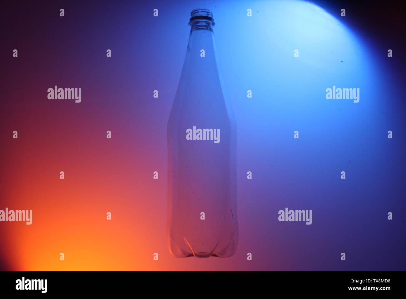 Close up di bottiglie trasparenti su uno sfondo colorato con illuminazione artificiale Foto Stock