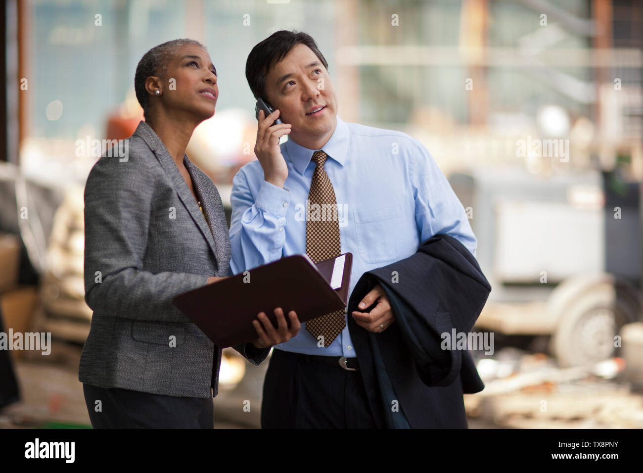 Due colleghi di lavoro per discutere i piani per un progetto su un sito in costruzione. Foto Stock