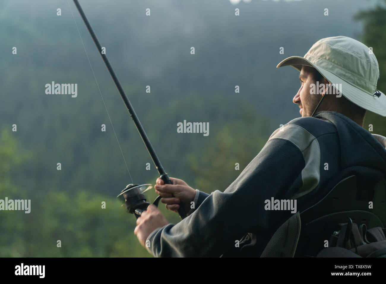 Giovane uomo su una sedia a rotelle la pesca al bel lago tramonto, alba Foto Stock
